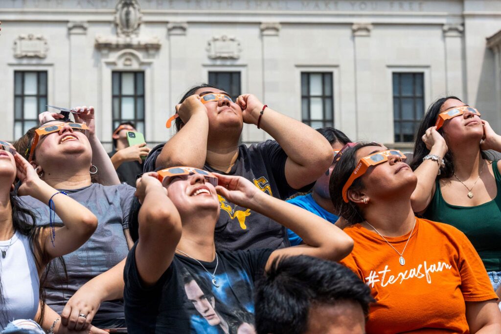 Students, Faculty and staff on campus looking up at the eclipse through longhorn eclipse glasses.