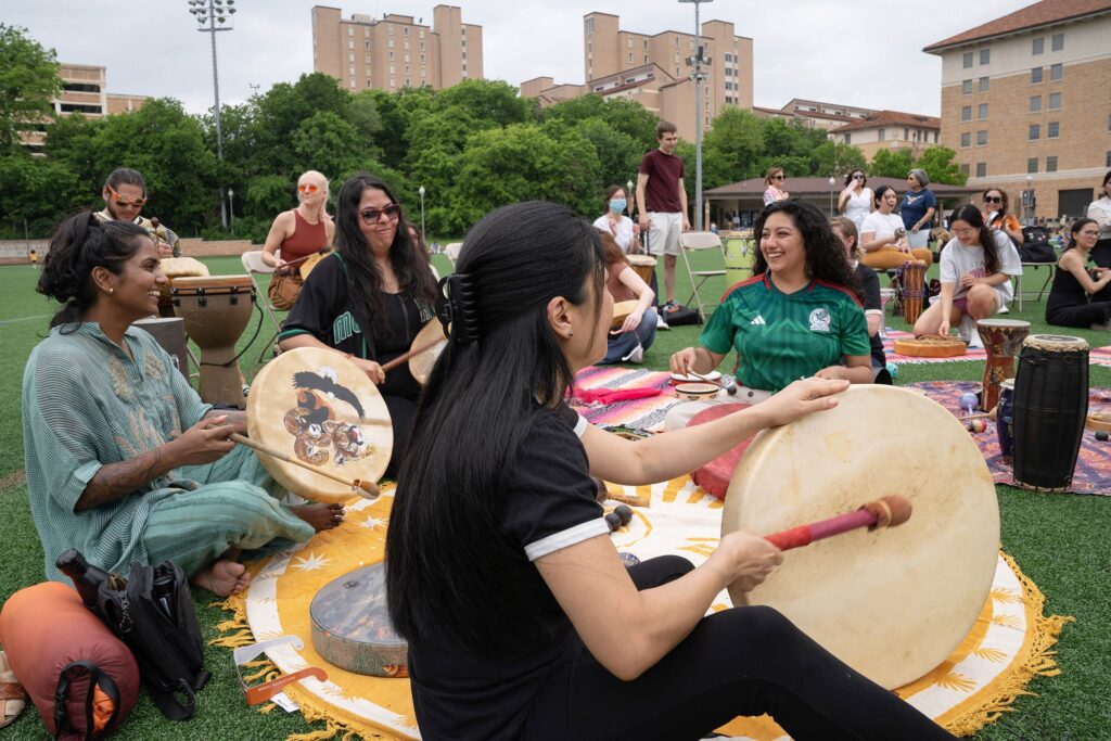 Students, Faculty and staff on campus listening to a drum circle planned event.